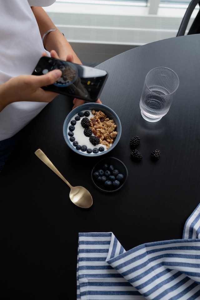 Content creator takes an image of her berries and granola breakfast bowl to create a post on Instagram.