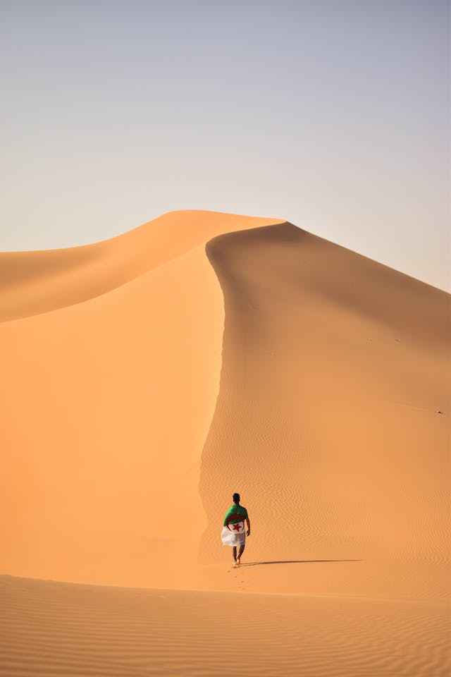 An influencer walks through the dunes in a desert.