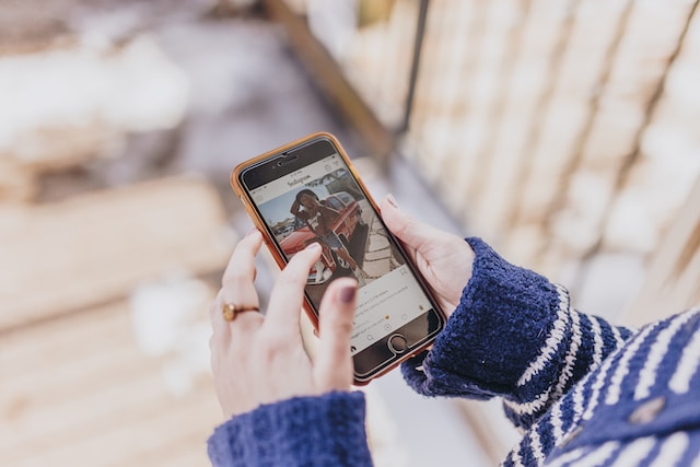 A person holding their smartphone with both hands and using Instagram.