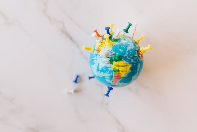 A small globe covered with push pins on a countertop.