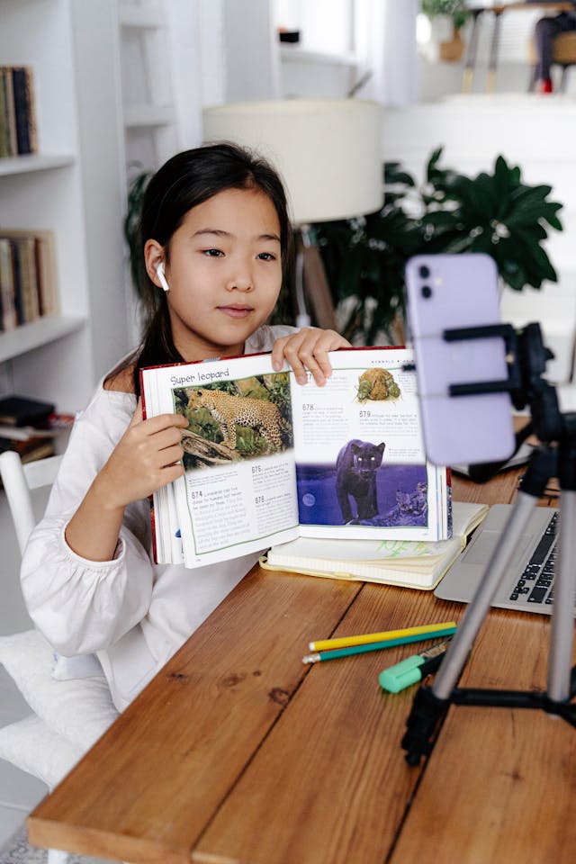 Uma jovem criadora mostra o seu livro a um telemóvel com câmara.