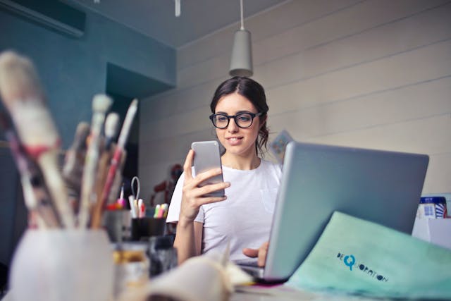 Une femme à lunettes fait défiler son téléphone portable.